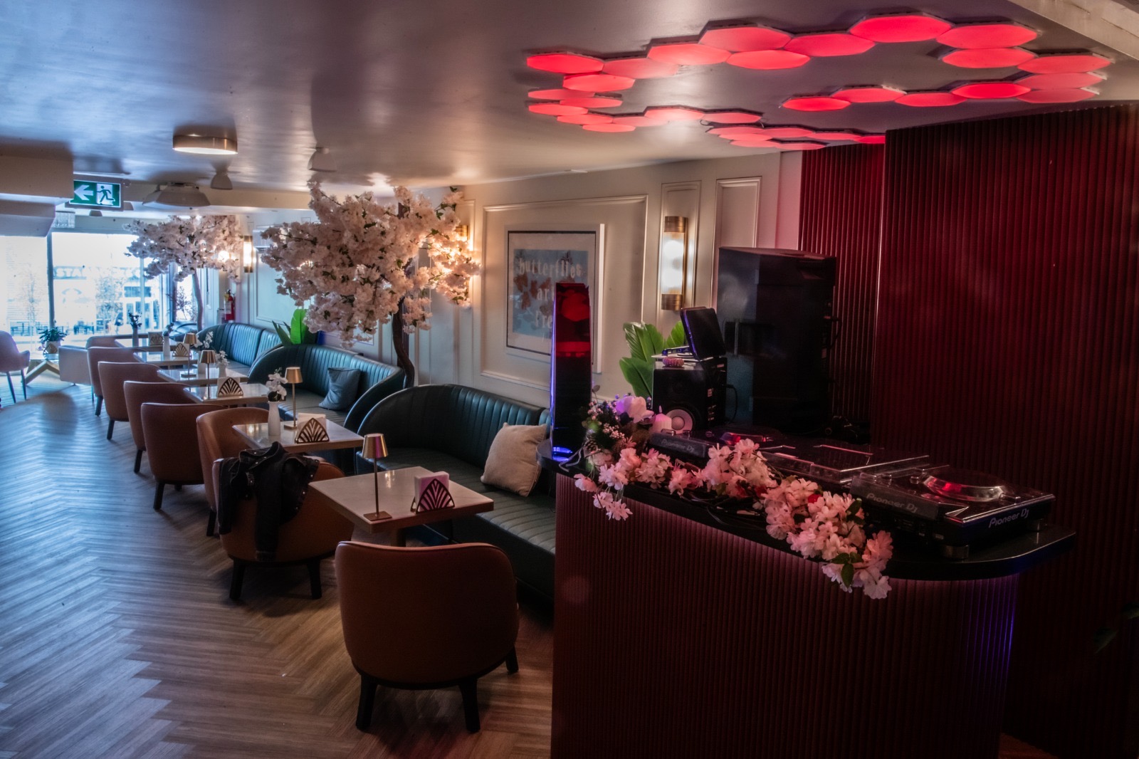 The DJ Booth — Blossom & Honeycomb Lights DJ booth framed by blossoms with red honeycomb ceiling lights at Yorkville Lounge