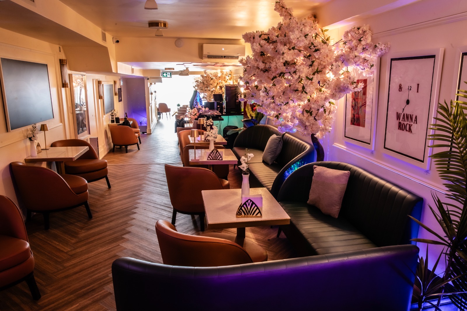 I Wanna Rock — Purple Hour Lounge view with 'I Wanna Rock' pop-art and blossom tree under purple lighting